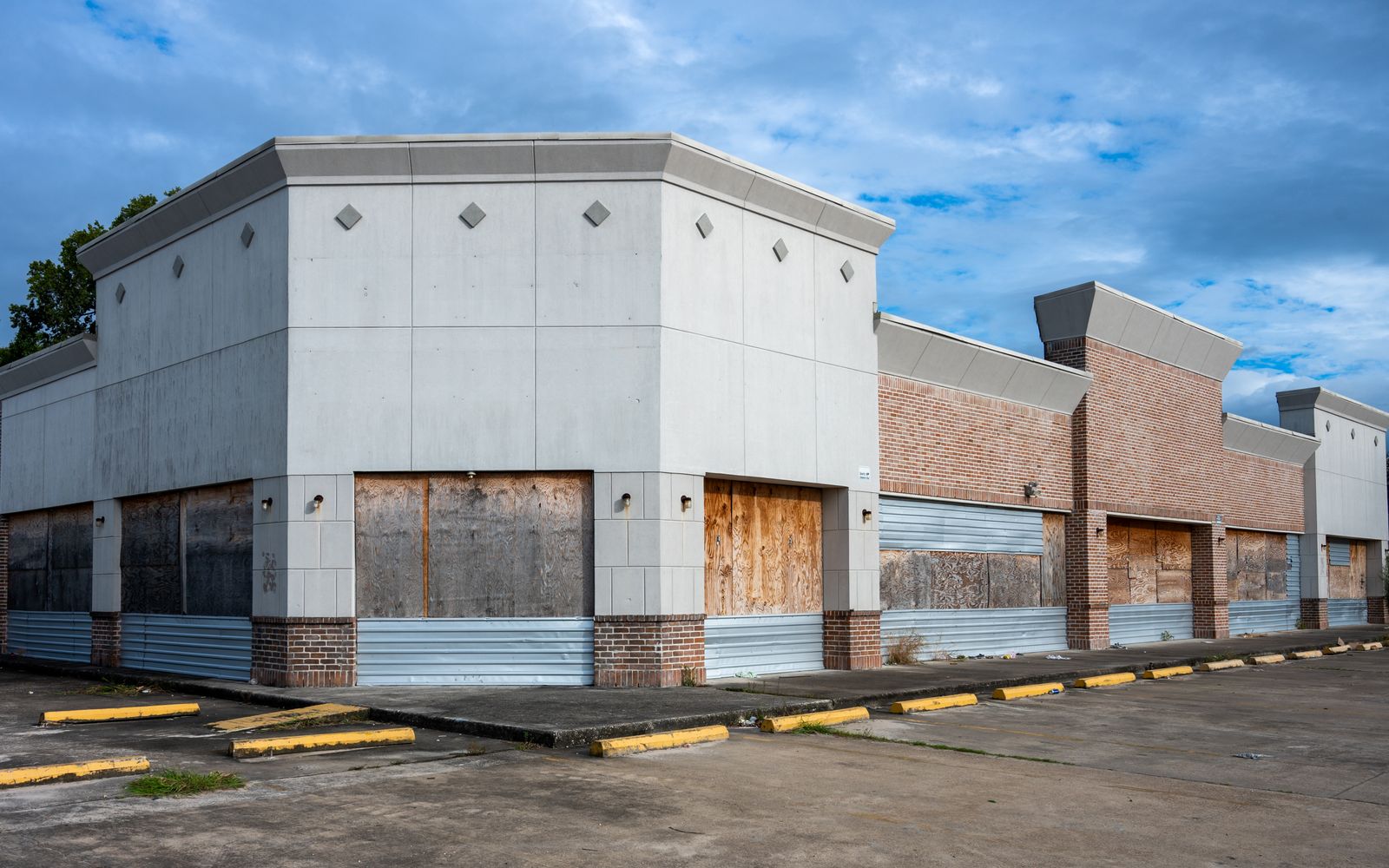 Vacant retail building with boarded storefronts and a secured, empty parking lot