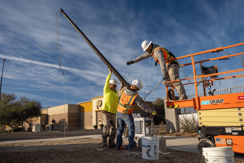 Crew installing a parking lot light pole outside a commercial building